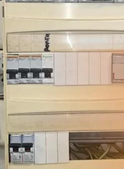 Avant : un ancien tableau électrique beige, avec des câbles visibles dans une rangée.